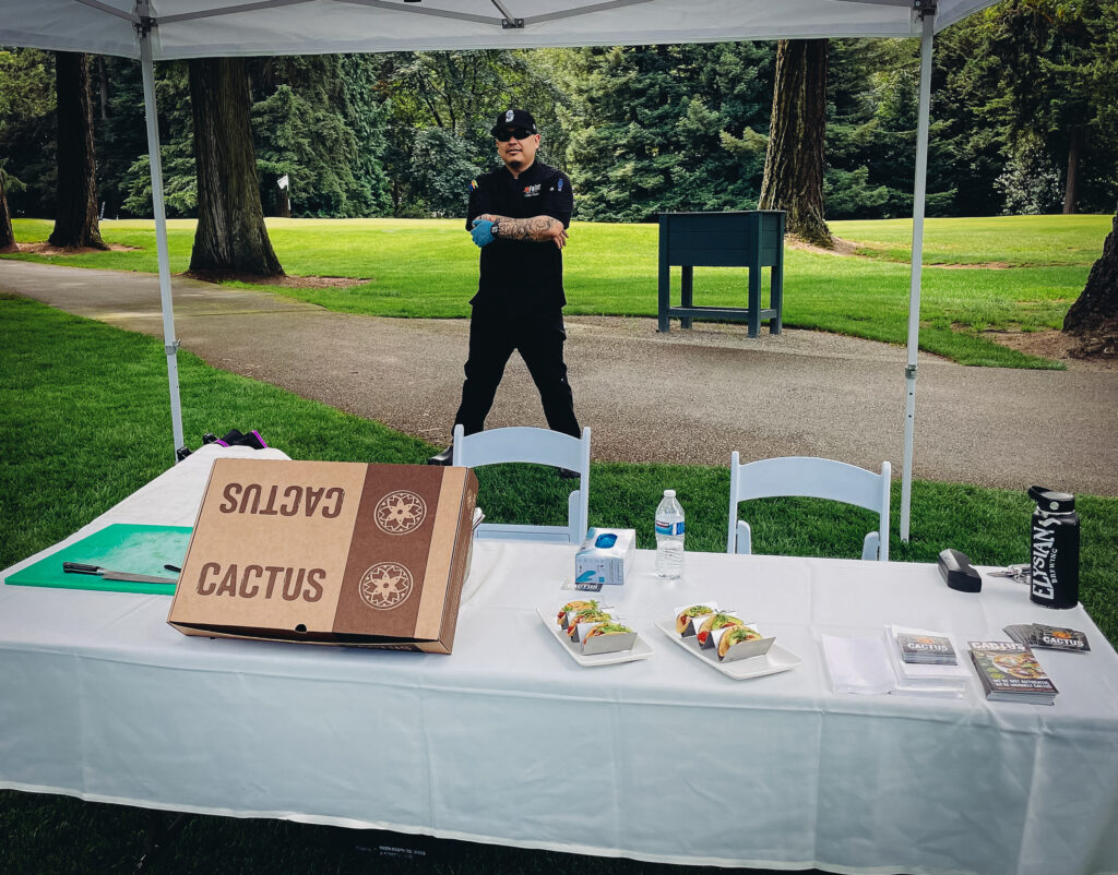 Kellan Kubo posing in front of the Cactus taco table.